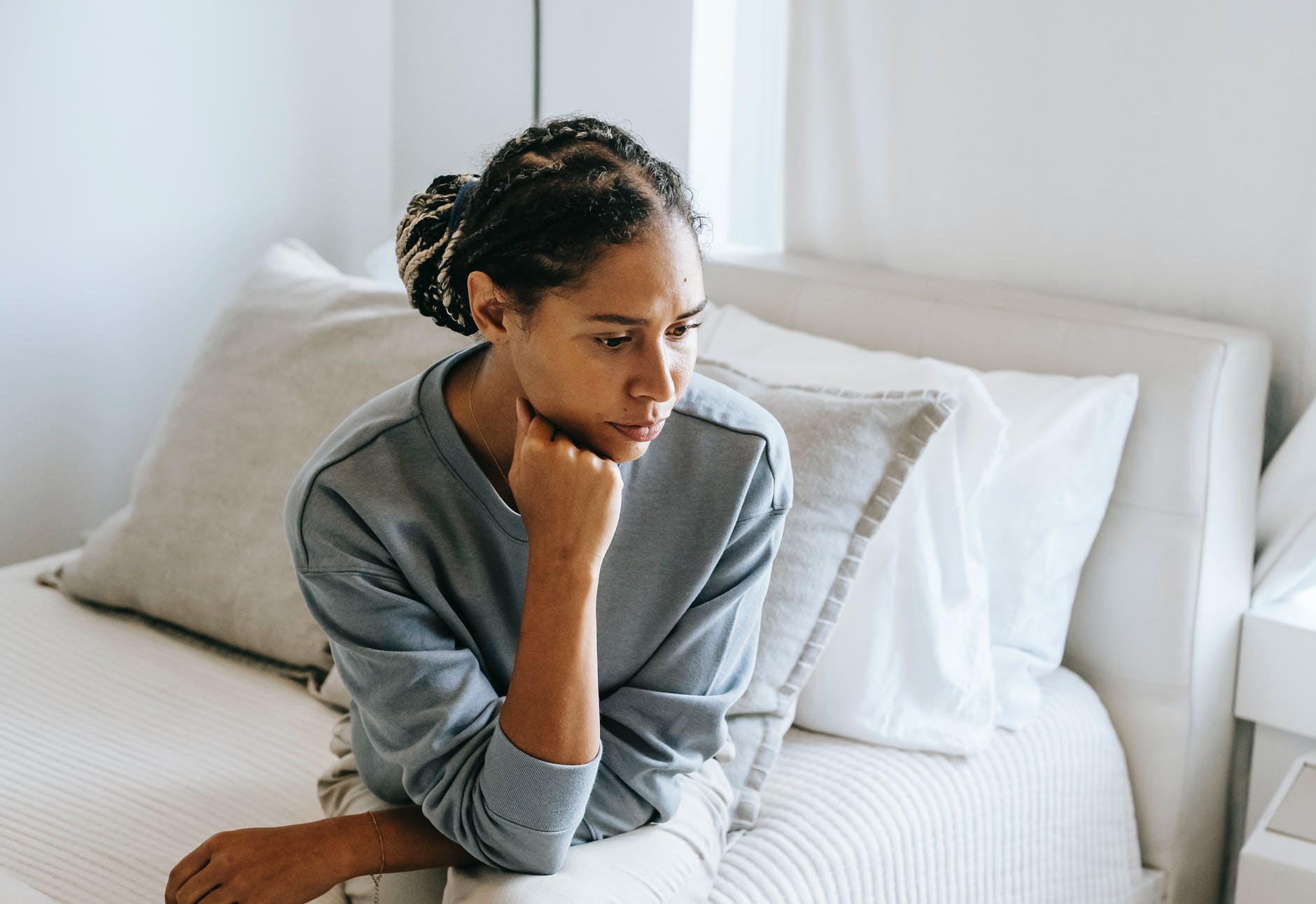 black woman sitting on bed in light room